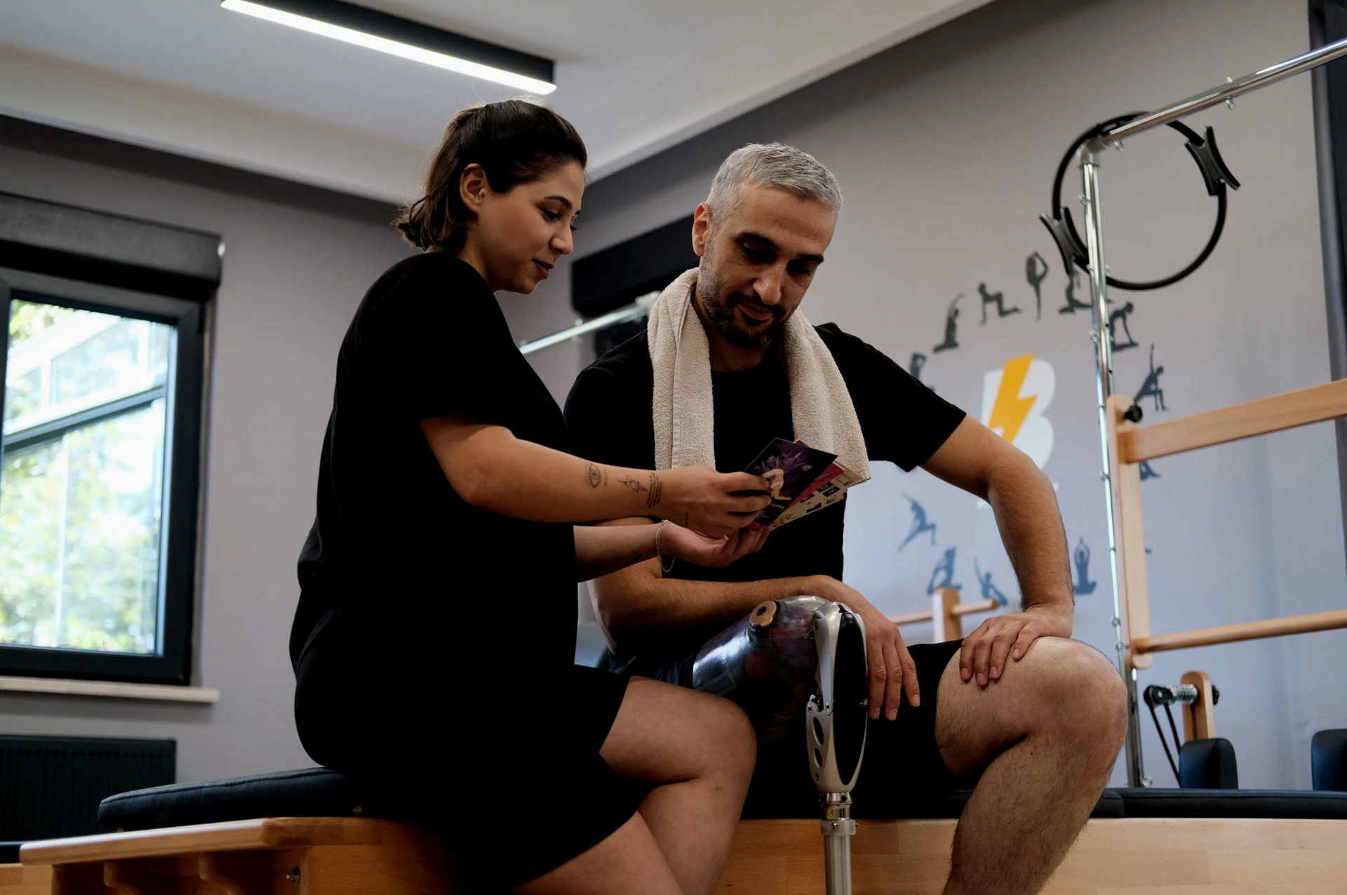 Physiotherapeutin behandelt Knie eines Patienten mit Therapieband